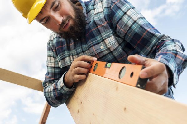 worker-with-hard-hat-level-checking-roof-timber-min